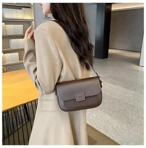 Detail of dark brown leather crossbody bag with mixed textures and square flap closure
