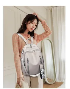 Detail of soft leather backpack featuring multi-zipper compartments and a geometric strap