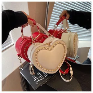 Detail of red and white heart-shaped handbags with gold chain trim and adjustable straps