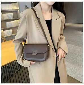 Close-up of brown crossbody square bag with leather and suede patchwork detail