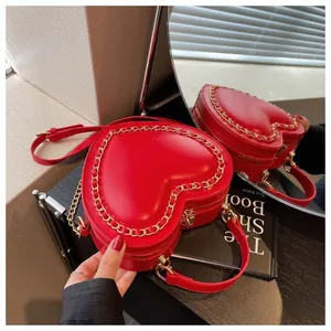 Detail of red heart-shaped handbag with golden chain trim and dual zipper closure system
