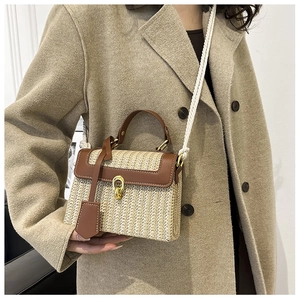 Dettaglio borsa in paglia intrecciata con finiture in pelle e chiusura dorata