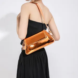 Close-up of bright orange glossy patent leather baguette bag worn by a model