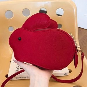 Sac à bandoulière rouge en forme de lapin avec chaîne dorée sur fond contrasté