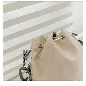 Detail of nylon bucket bag featuring silver eyelets and cream drawstring closure