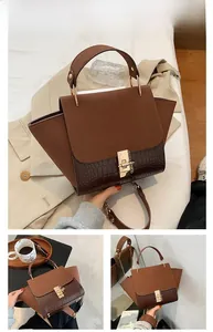 Detail of coffee brown trapezoid bag showing frosted texture and gold lock clasp