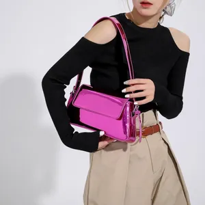 Detail of metallic bright pink baguette bag showing glossy finish and slim shoulder strap