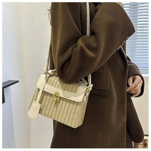 Dettaglio della borsa in paglia intrecciata con finiture in pelle bianca e chiusura oro