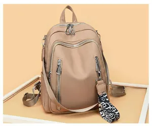 Close-up of beige faux leather backpack with multiple zippers and patterned wide strap