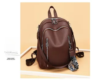 Macro shot of dark brown pebbled leather backpack showing multi-compartment silver zippers