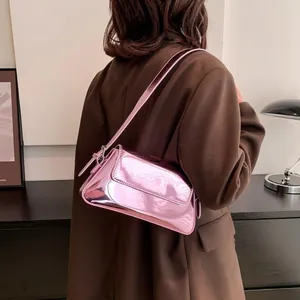 Pink glossy patent leather baguette bag shown as a stylish crossbody on a person