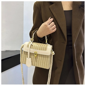 Dettaglio borsa di paglia con finiture in pelle crema e chiusura dorata su modella