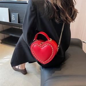 Red heart-shaped shoulder bag with gold chain trim and adjustable metal strap