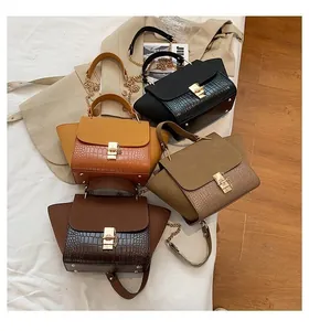 Detail of four matte leather trapezoid bags with crocodile pattern and metal locks