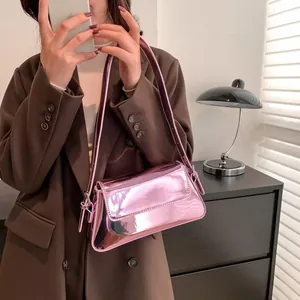 Macro detail of metallic pink baguette bag showing high-gloss mirror texture and strap
