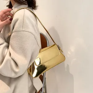Chic golden metallic baguette bag shown styled with a neutral tweed coat for women