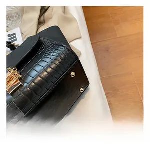 Close-up of black crocodile embossed texture with golden rivets and metallic hardware
