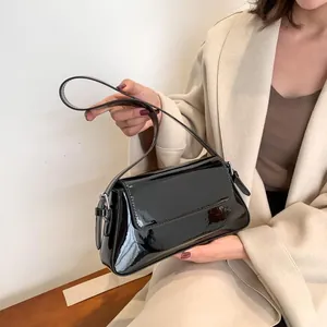 Detail of glossy black patent leather shoulder bag with sleek mirror finish and flap