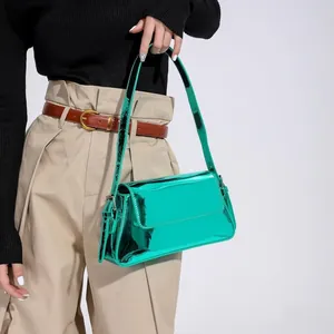 Detail of glossy green patent leather baguette shoulder bag with metallic finish