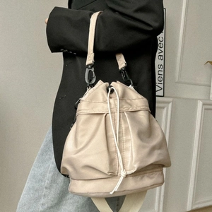 Beige nylon drawstring bucket bag with sporty shoulder strap shown on a model