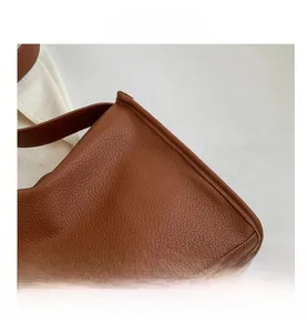 Detailed macro view of the caramel brown lychee leather texture and stitched handle joint