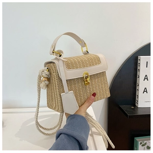 Dettaglio della borsa in paglia intrecciata con finiture in pelle crema e fibbia dorata