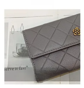 Macro detail of grey quilted long wallet with elegant golden petal-shaped metal twist lock