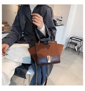 Detail view of contrast brown and black textured leather handbag with gold buckle