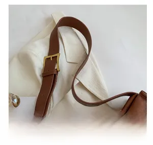 Detail of brown lychee texture leather handbag with golden adjustable buckle strap