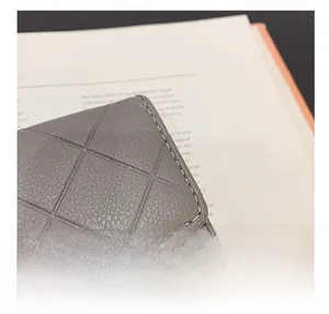 Detail showing grey quilted leather wallet with precise stitching and pebble texture