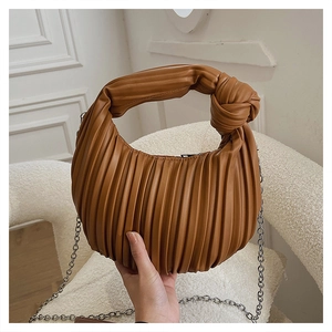Détail du sac plissé caramel montrant la poignée nouée et la bandoulière en chaîne