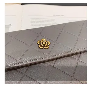 Detail of grey quilted long wallet featuring a vintage gold camellia flower metal clasp