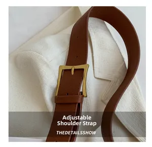 Detail of adjustable brown lychee pattern leather shoulder strap with gold metal buckle
