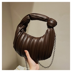 Détail d'un sac à main plissé marron foncé avec poignée nouée et fine bandoulière chaîne
