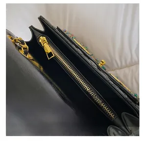 Detailed macro view of the smooth gold metal zipper and glossy black leather bag texture