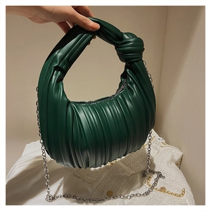 Gros plan d'un sac plissé vert foncé avec poignée nouée et chaîne en métal argenté
