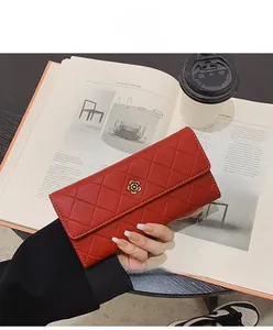 Detail of red quilted long wallet with golden floral buckle held in hand stylishly