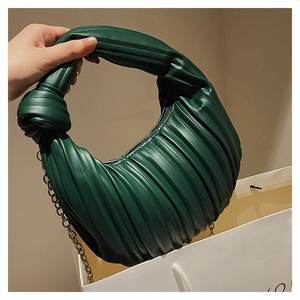 Détail du sac plissé vert foncé avec poignée à nœud souple et fine chaîne en métal
