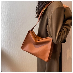 Detail view of caramel pebbled leather tote bag with gold buckle and adjustable strap