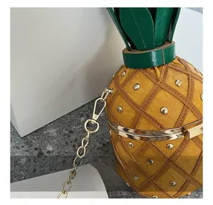Détail du sac seau ananas avec clous dorés, crochets métalliques et couvercle en feuilles