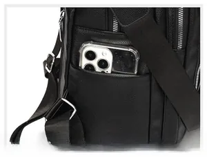 Detail of black lychee leather backpack side pocket holding a smartphone for scale