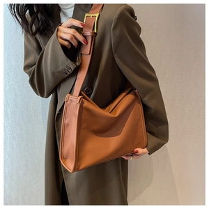 Detail of tan lychee-textured leather shoulder bag with gold hardware on female model
