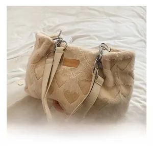 Detail of plush beige tote bag with embossed heart pattern and metallic chain handle