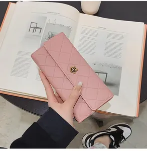 Detail of pink quilted leather long wallet featuring a floral clasp on a fashion magazine