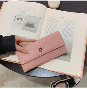 Detail of pink quilted long wallet with flower emblem held over an open magazine