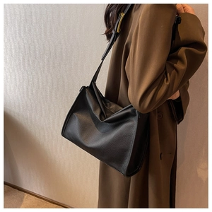 Detail of black lychee texture leather handbag with adjustable gold metal buckle strap