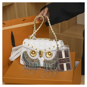 Close-up of white owl-shaped crossbody bag with gold rivets and colorful beaded tassels