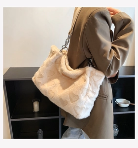 Model wearing a fuzzy cream heart tote bag with metal chain strap for autumn style