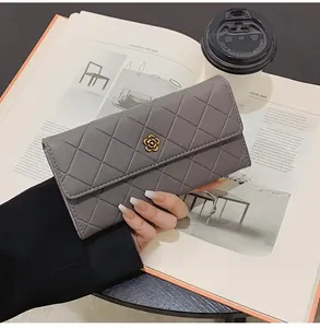 Close-up of grey quilted leather wallet with gold camellia buckle held by model