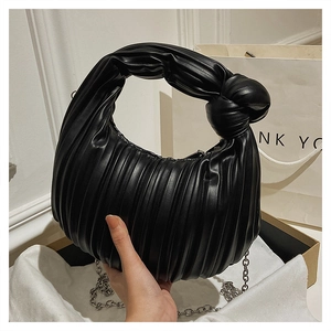 Détail du sac plissé noir avec poignée nouée et bandoulière en chaîne métallique argentée